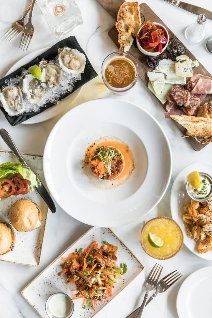 Several individually plated restaurant dishes and drinks spread across a table