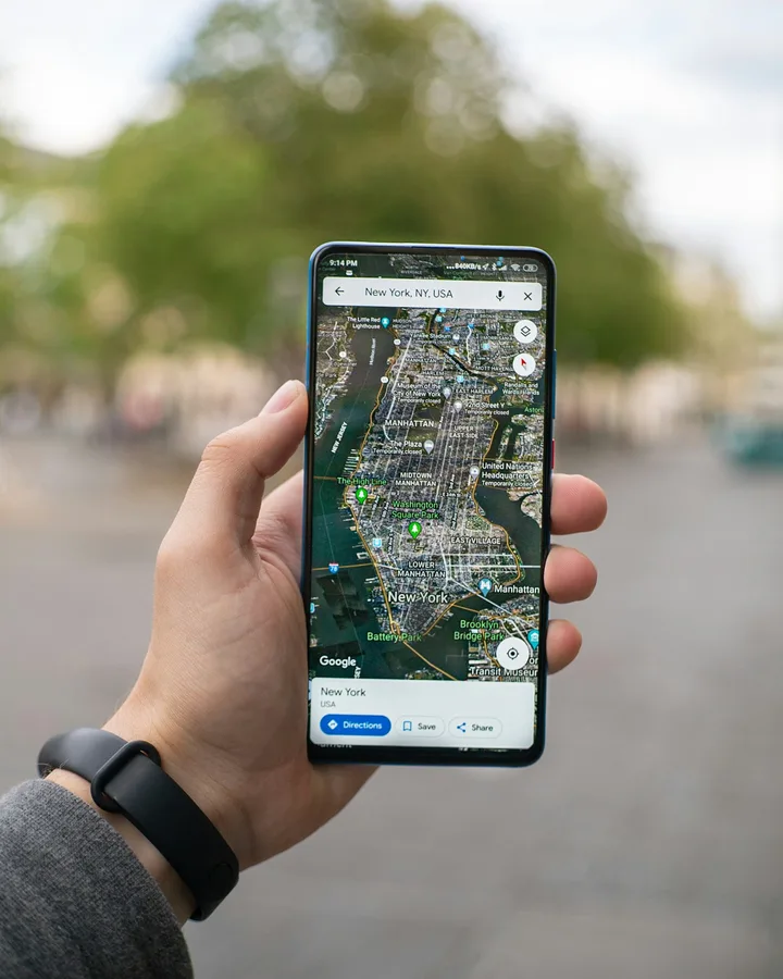 Hand holding a phone with a map app open on a city street