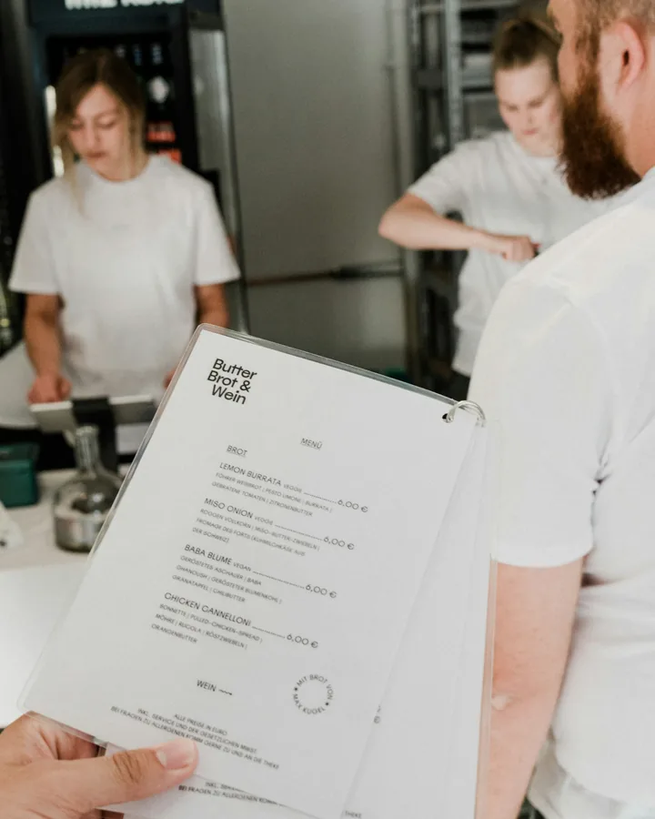 Restaurant staff holding a printed menu in the kitchen
