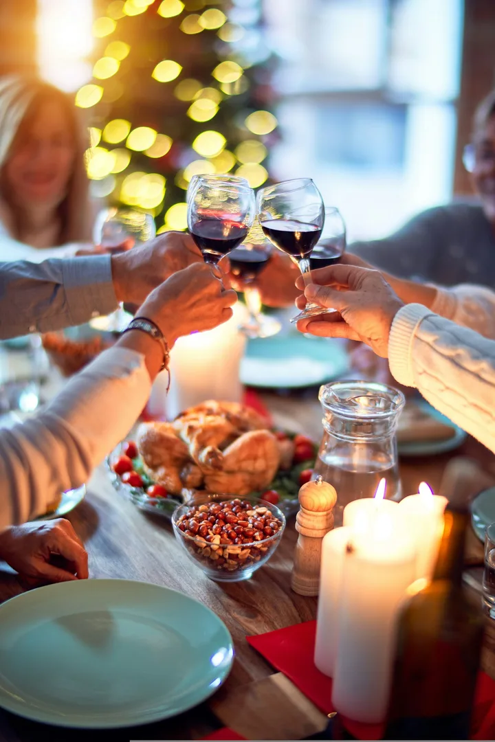 Group raising glasses of red wine over a festive dinner table with candles