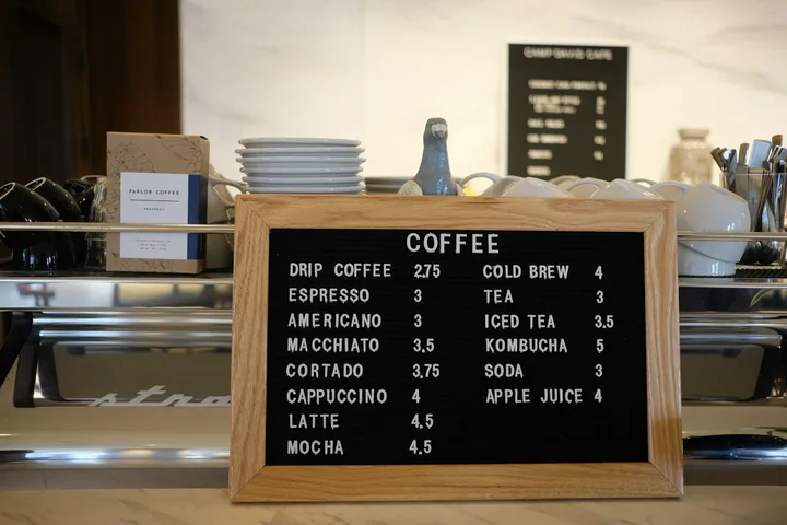 Letter board on a café counter listing coffee drinks and their prices