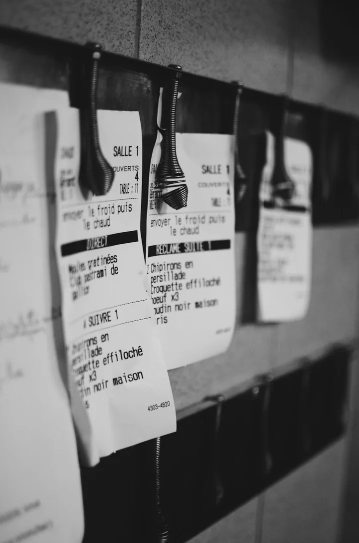 Paper order tickets clipped to a rail in a restaurant kitchen