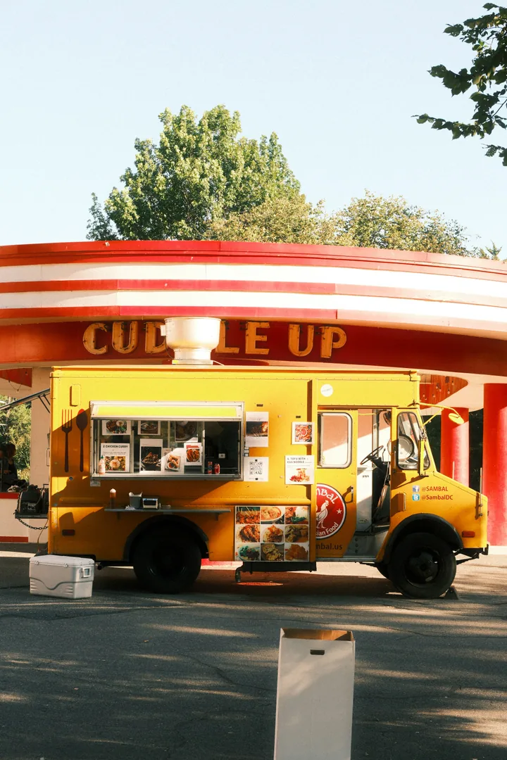 Yellow food truck with dish photographs displayed around its service window