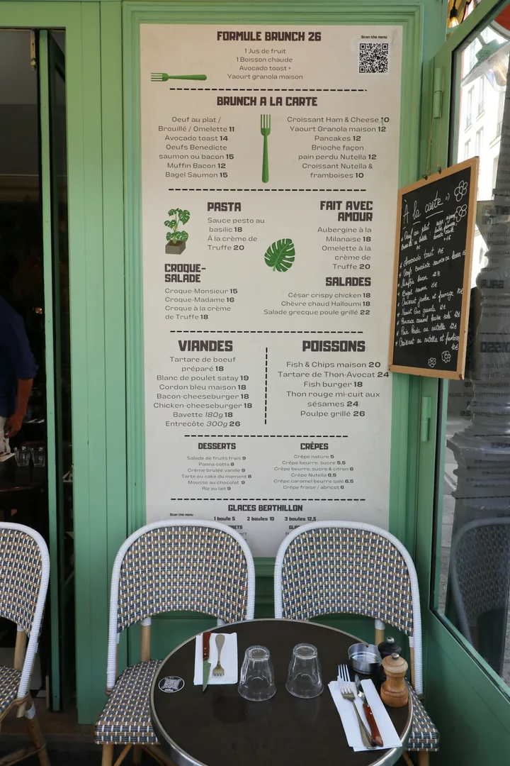 Cafe menu board showing dishes, prices and a QR code beside a table