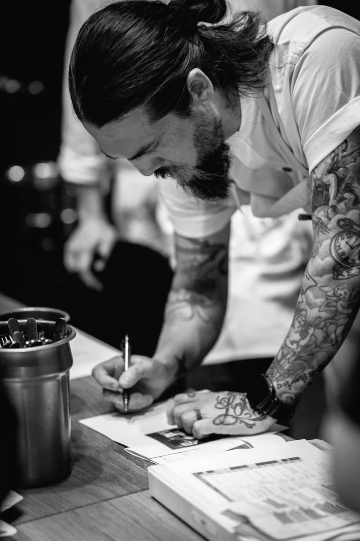 Chef writing notes on a printed sheet at a table