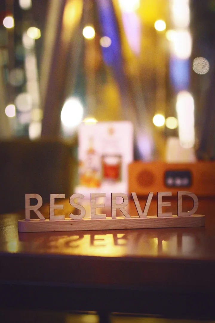 Wooden Reserved sign on a table with blurred lights behind it