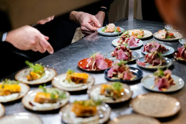 Kitchen team arranging several small plates before service