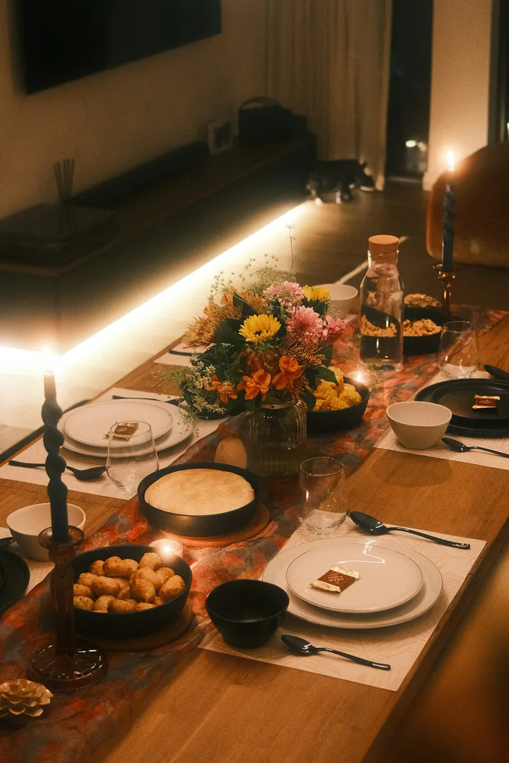A long dinner table set with plates, flowers and candles
