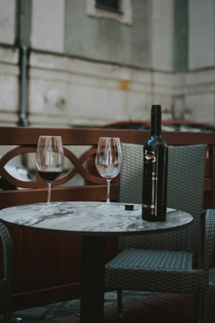 Two glasses of red wine and a bottle on a small outdoor café table