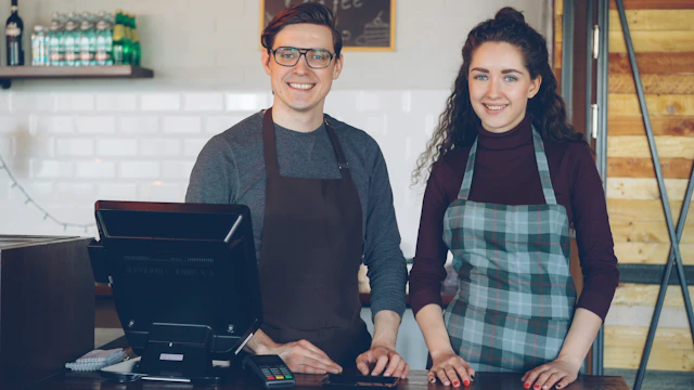 Two café workers smiling behind the counter